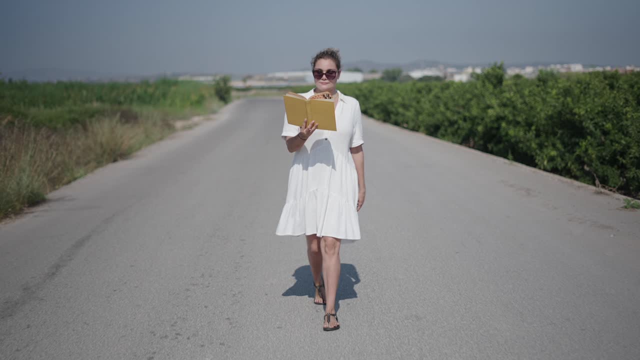 Donna che legge un libro su una strada di campagna