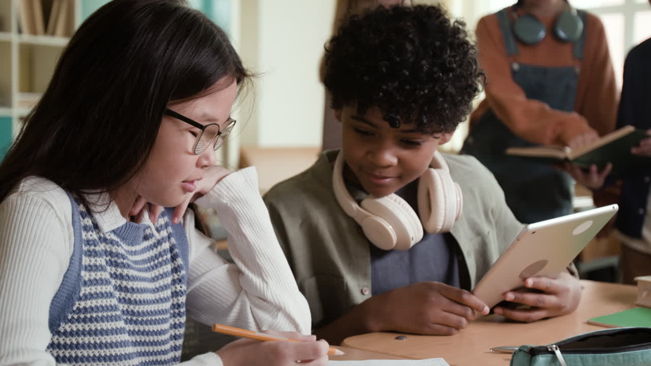 Young students collaborate with a tablet and notebook in a classroom