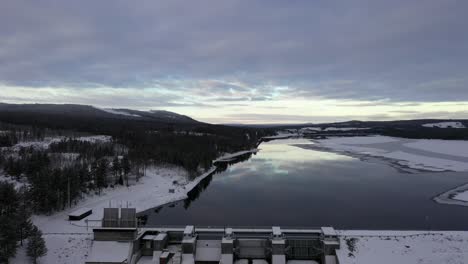 Traumhaftes-Zurückziehen-Der-Antenne-über-Spiegelreflexion-Im-See,-Enthüllen-Damm,-Wald-Winterlandschaft,-Asendammen,-Schweden