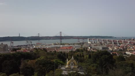 majestic aerial forward flying over beautiful and historical park in downtown lisbon, with the river tagus and the bridge in the background