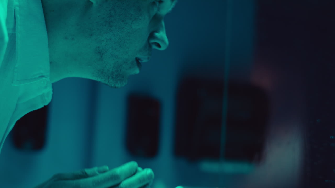 Man washing face in a teal-lit room