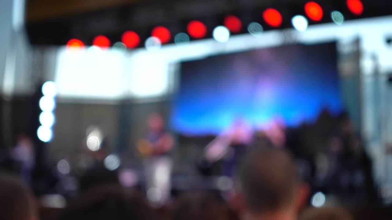 Concerto sul palco. Folla di persone e musicisti sulla scena. Fuori fuoco