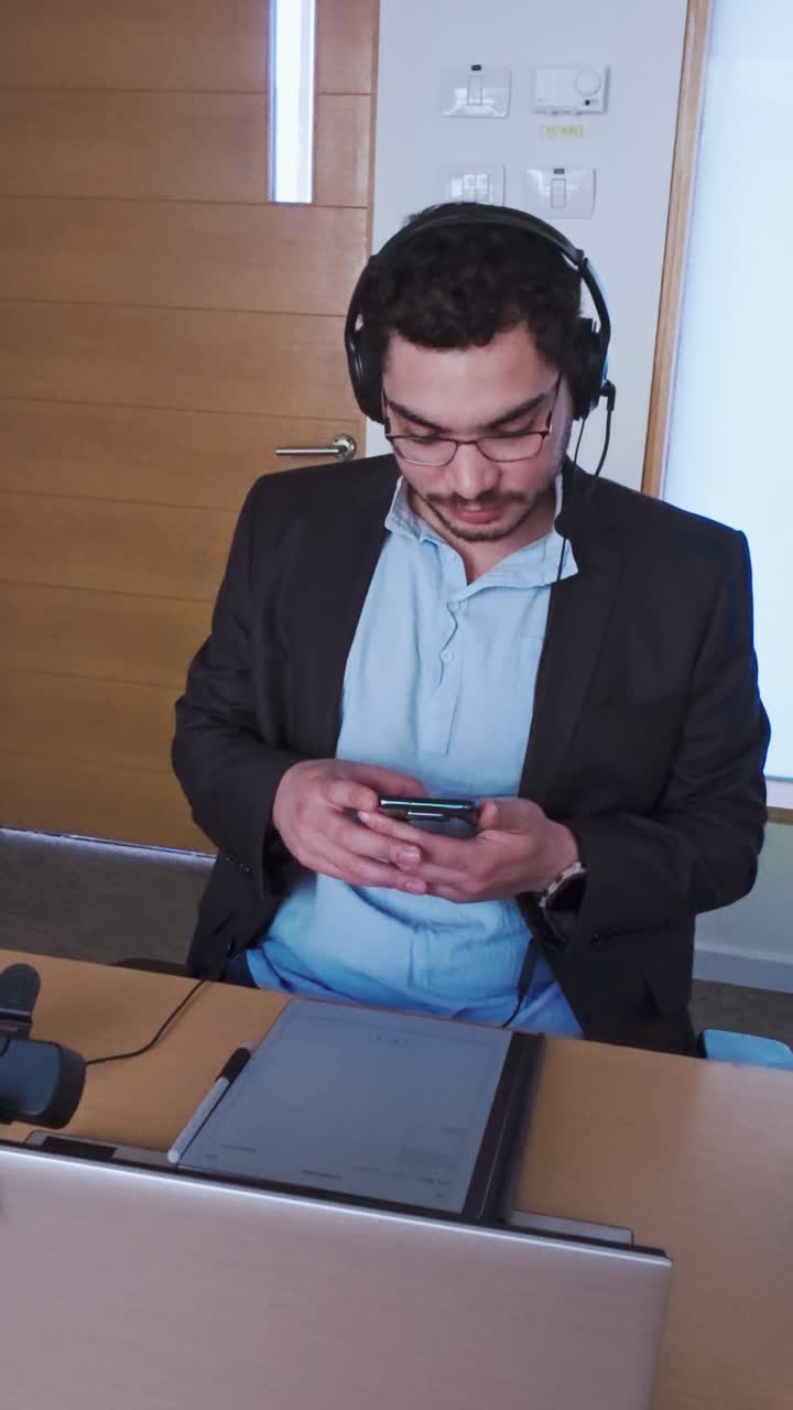 Businessman with Headset Texting on His Mobile Phone in the Office