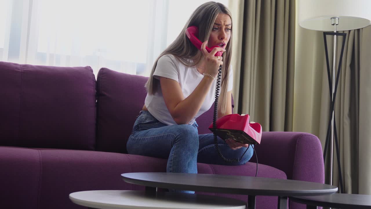 Young Woman Talking Old Rotary Landline Telephone While Sitting on Couch in Living Room
