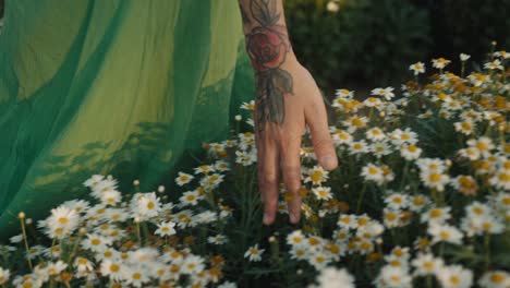 woman in a green dress walking through a field of flowers
