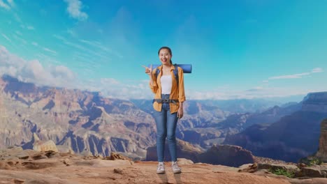 full body of asian female hiker with mountaineering backpack smiling and pointing to side while traveling at the top of mountain