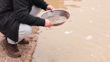 person panning for gold in muddy water