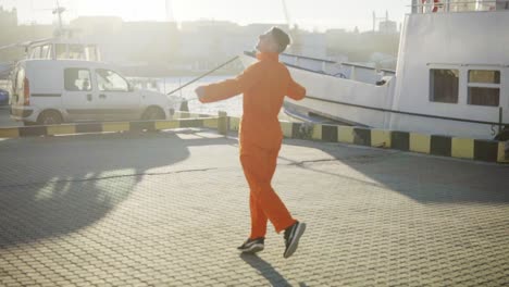 Young-harbor-worker-in-orange-uniform-is-turning-around-in-the-son.-Happy-young-man-is-celebrating-something