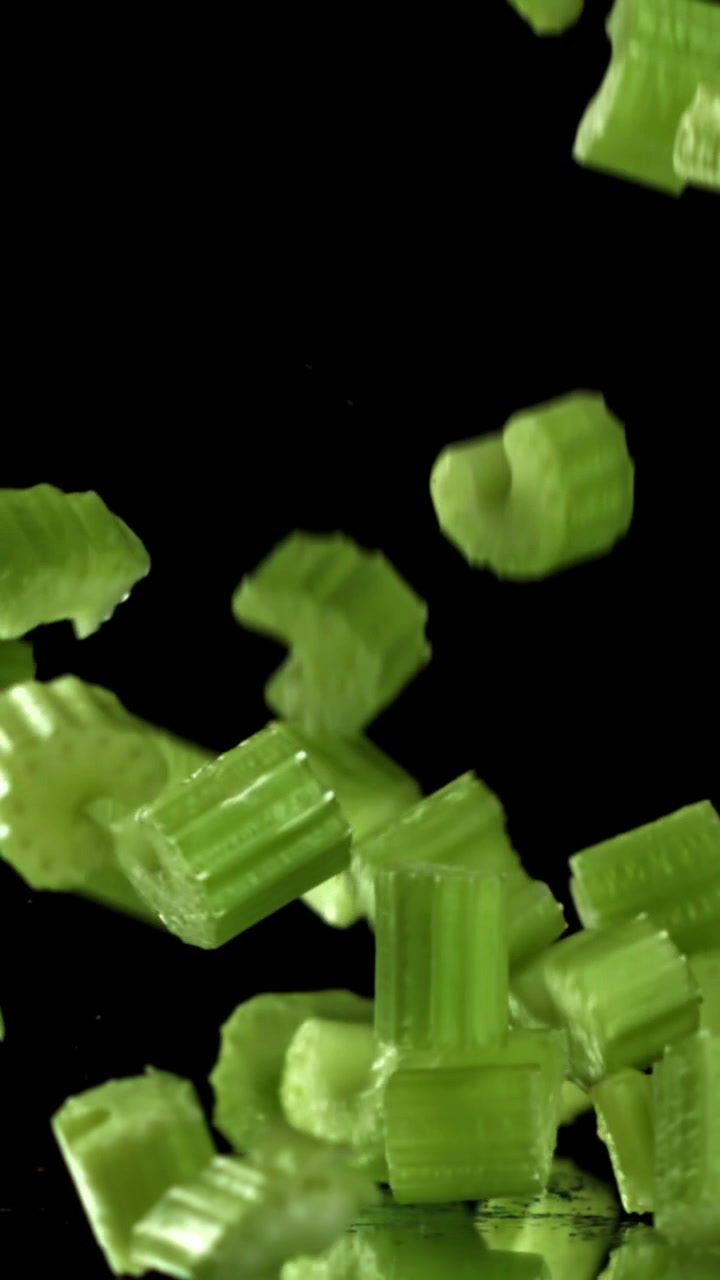 Chopped Celery Pieces Falling in Slow Motion on Black Background