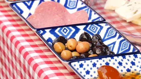 a spread of olives, salami, and cheese on a red and white checkered tablecloth