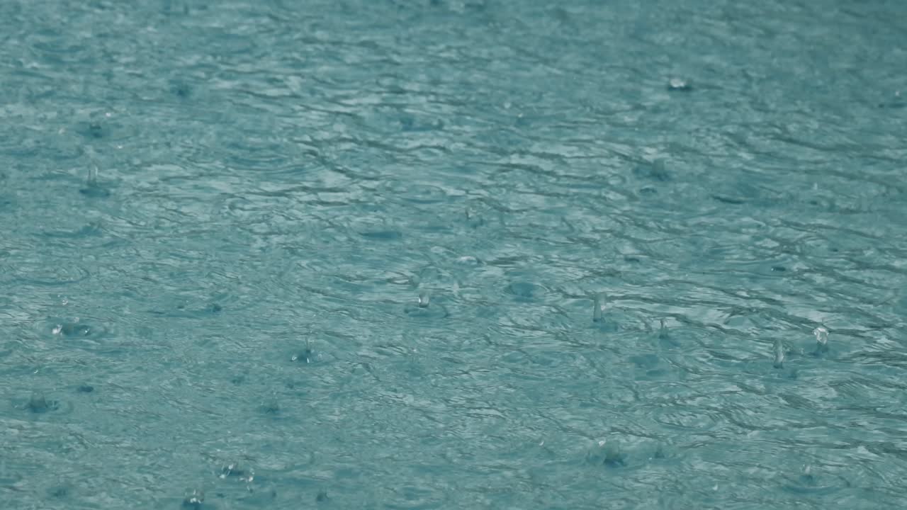 Close-up view of raindrops impacting a water body
