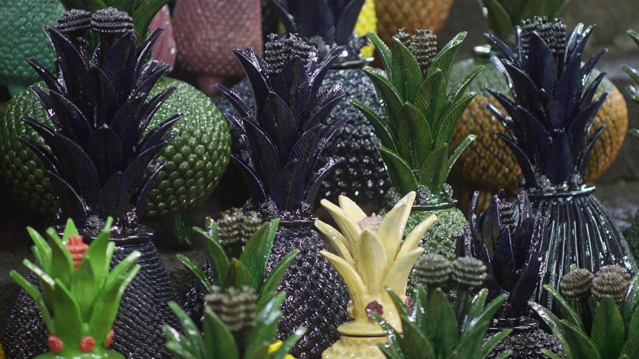 Colorful ceramic pineapple decorations displayed at artisan craft market, sparkling backdrop