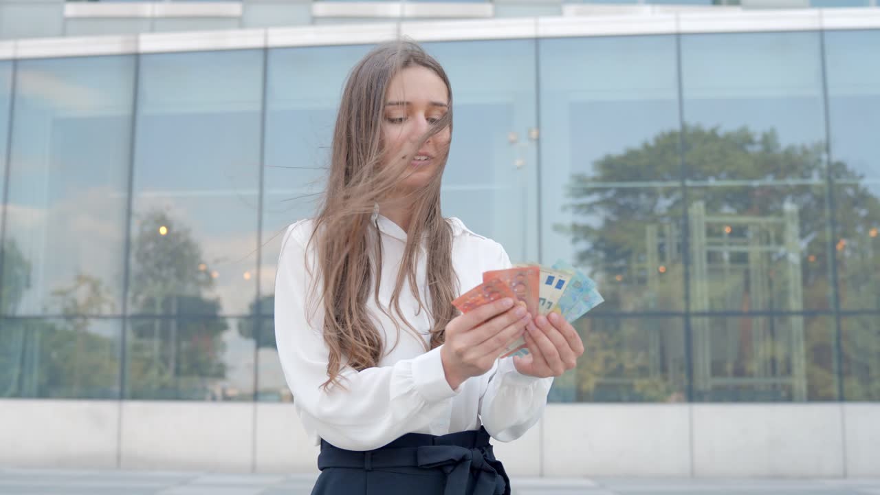 Business woman counts euro's outside of modern office building