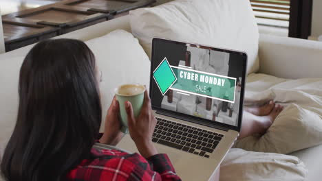 Biracial-woman-on-couch-with-coffee-using-laptop-for-online-shopping,-slow-motion