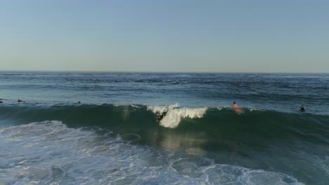 aerial shot group of surfers in the water, one bodyboarder catch a breaking wave, faro