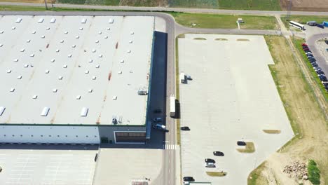 Aerial Shot of Industrial Warehouse Loading Dock where Many Truck with Semi Trailers Load Merchandise