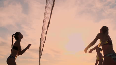 Beachvolleyball-Match-Mädchen-Schlagen-Den-Ball-In-Zeitlupe-Bei-Sonnenuntergang-Auf-Dem-Sand