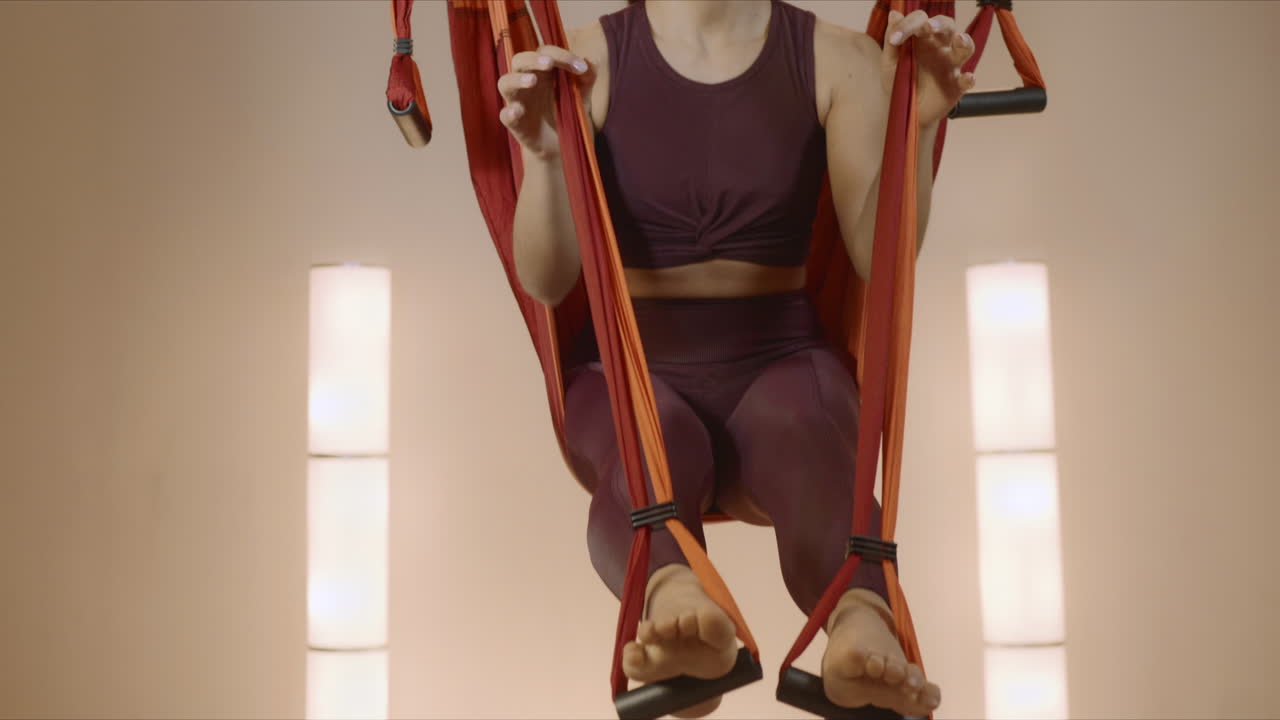 mujer poniendo los pies en correas de yoga en clase. mujer haciendo aero yoga en hamaca