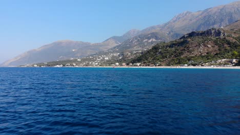 horizonte marino azul bordeado por playa de arena y paisaje montañoso en pueblos turísticos en albania