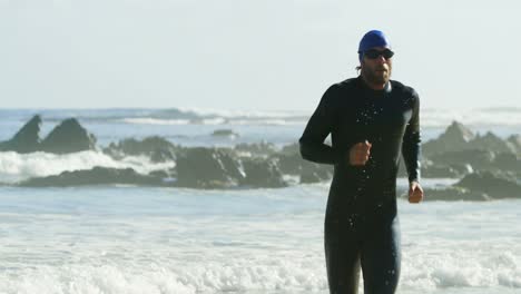surfista masculino corriendo en la playa