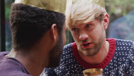 Gay-Male-Couple-Sitting-Around-Table-For-Christmas-Dinner-Talking-And-Making-A-Toast