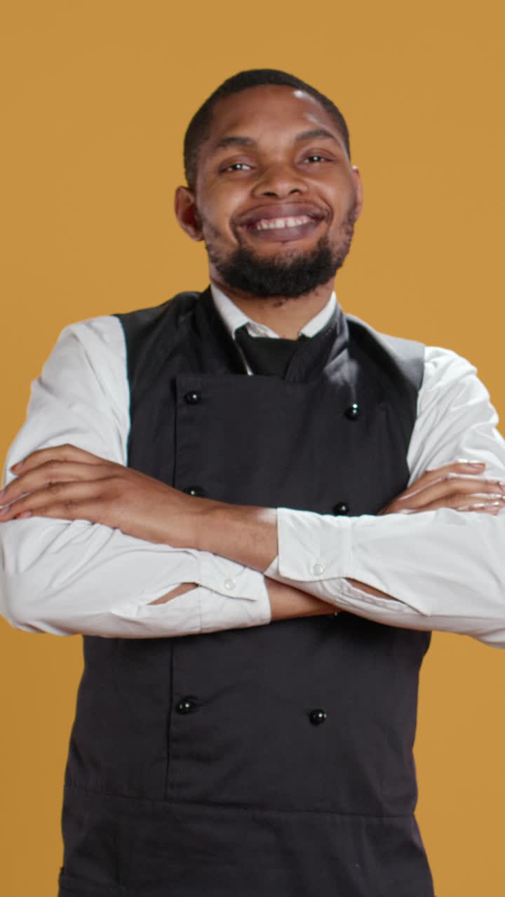 Chef afroamericano sorridente che posa a braccia conserte