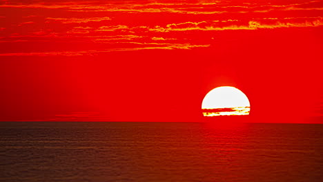 bright sun moving in the red sky setting over calm sea. - timelapse