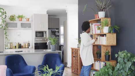 Happy-african-american-woman-talking-on-smartphone-standing-in-living-room-at-home,-slow-motion