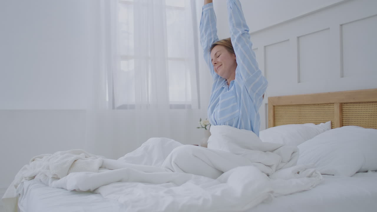 una joven se despierta por la mañana en el hotel y se alegra bebiendo y sonriendo
