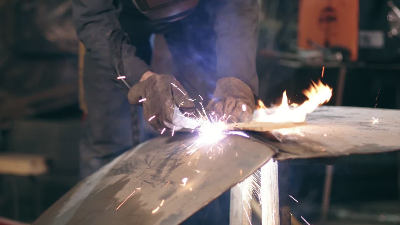 Male worker in protective gloves and workwear is cutting off metal piece with oxy acetylene cutting torch at a factory. Slow motion footage.