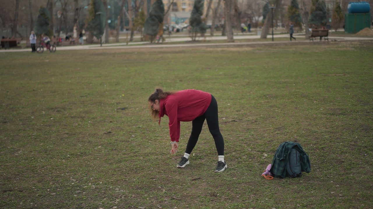 Woman Organizing Belongings Outdoors, Female Individual Tidies Up Items In Park Environment, Woman Carefully Organizes Her Gear And Clothing Within Peaceful Park Setting During Leisure Time