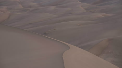 panning up to stunning mountain range behind sand dune field at sunrise