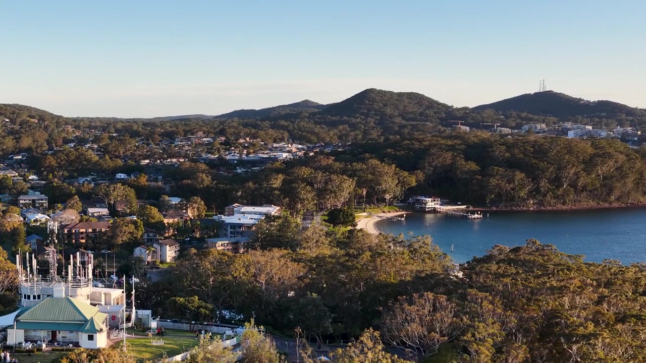 Ampia ripresa aerea della costa di Nelson Bay con edifici residenziali e foresta lussureggiante in Australia
