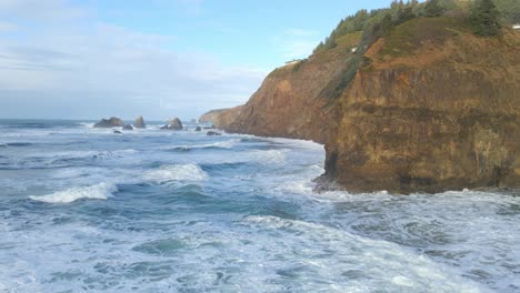 revealing scene of ocean waves roll into a beautiful oregon coast beach with cliffs in the background