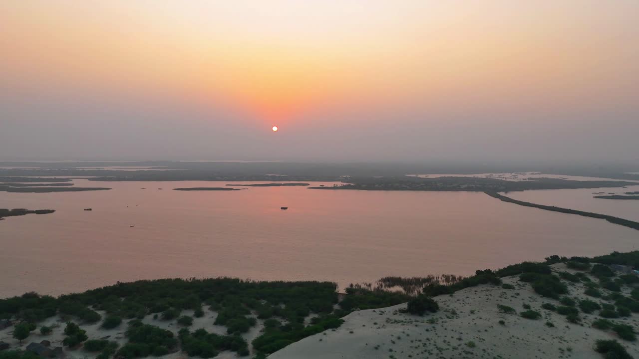 Droneoptagelse af solopgang over kystlinjen ved Baqar-søen i Pakistan.