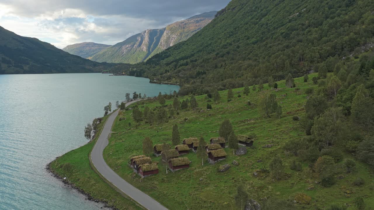 Trehytter koselig plassert ved et isbrevann og fjell i Norge