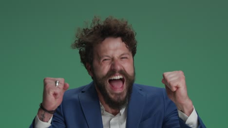 crazy businessman holding fists in the air, screaming and cheering victory, being the winner, making funny and dynamic, energy faces on green background