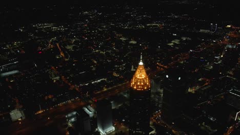 an approaching drone shot of a lit up skyscraper downtown