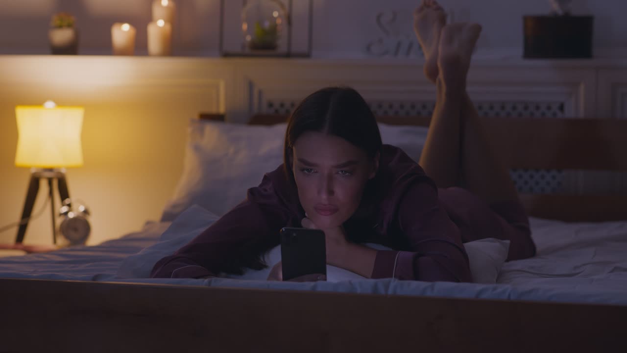 밤에 침대에서 드폰을 사용하는 여자
