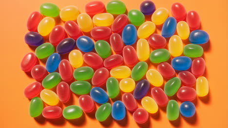 a colorful assortment of jelly beans on an orange background