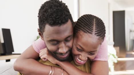 Happy-african-american-couple-smiling-and-embracing-on-couch-at-home,-in-slow-motion