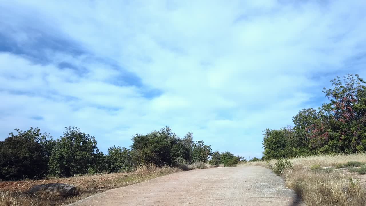 A peaceful walking path winds through a lush Cyprus valley near Souni Forest. A building rises atop the hill, blending countryside charm with quiet development in Limassol’s rural landscape.