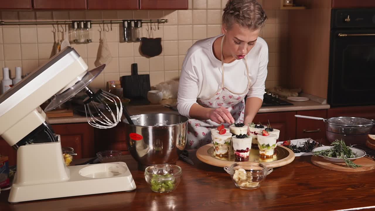 mujer haciendo postre de frutas en capas en la cocina
