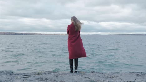 woman in red coat by the lake