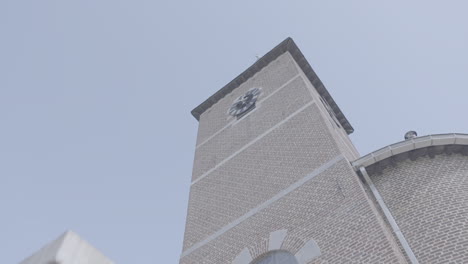 Low-Angle-Aufnahme-Eines-Kirchturms-In-Belgien-In-Zeitlupe-Vor-Blauem-Himmel-An-Einem-Sonnigen-Tag