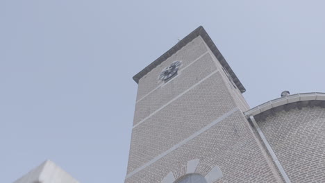 Low-angle-shot-of-a-church-tower-in-Belgium-in-slowmotion-agains-a-blue-sky-on-a-sunny-day-LOG