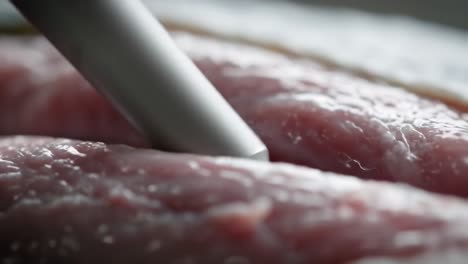 demonstrating an effective method for tenderizing pork fillets using a handheld tool in a clean kitchen. this technique helps enhance flavor and texture for perfect meals.