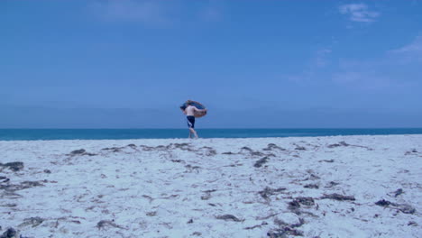 A-boy-runs-with-a-skimboard-on-a-beach