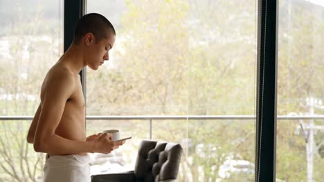 man using mobile phone while holding coffee cup at home 4k