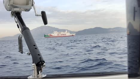 literal shot from fishing boat of big ship sailing in blue ocean